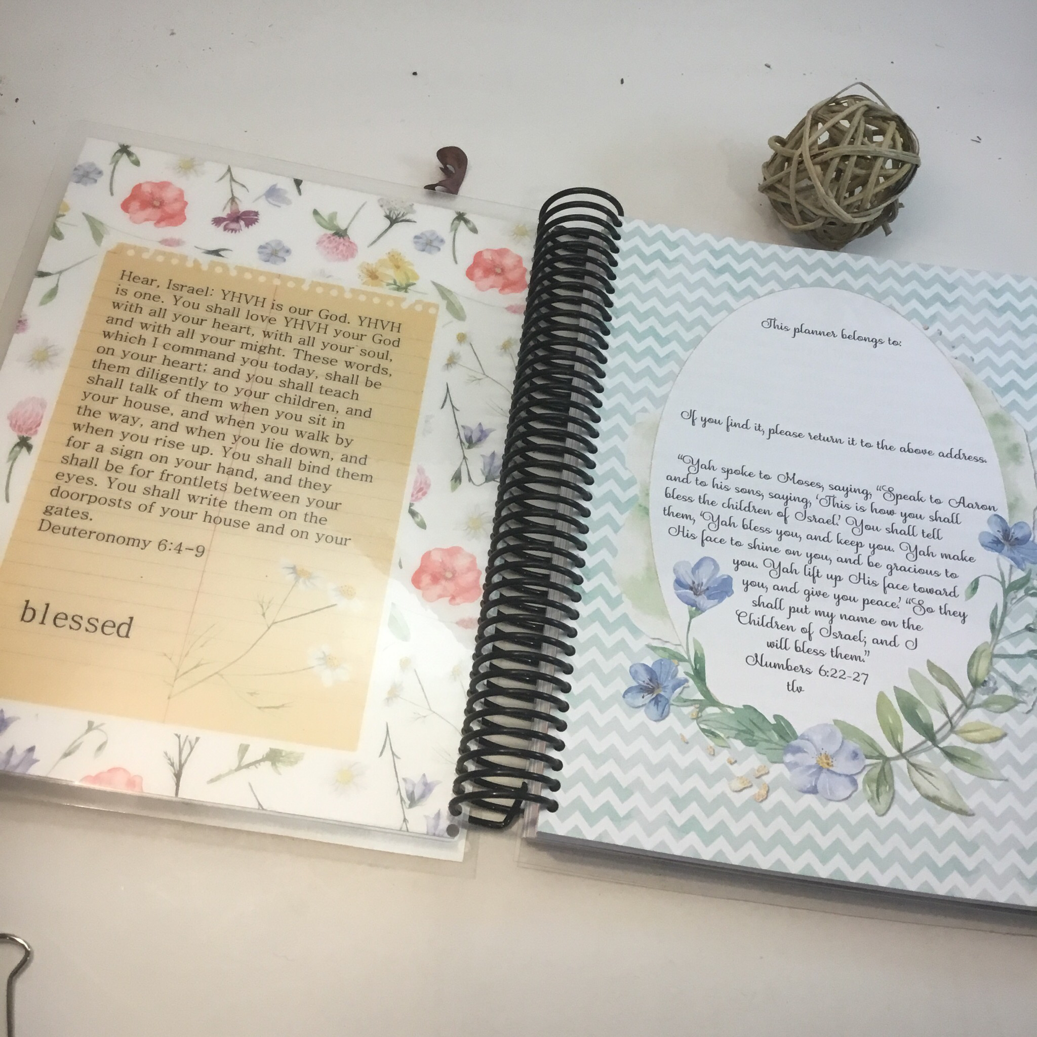 An open spiral-bound planner showing the coil binding, laminated cover, and lay-flat pages